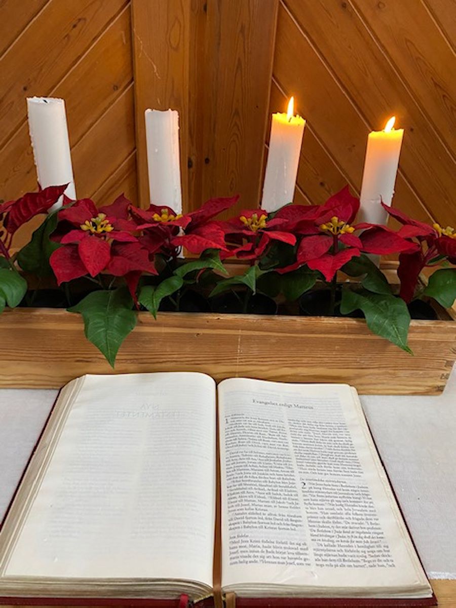 Altare med bibel och två tända adventsljus i adventsljusstake med fyra ljus och julblommor, Equmeniakyrkan Hallunda [foto: Carlota "Carro" Bocio Duff]